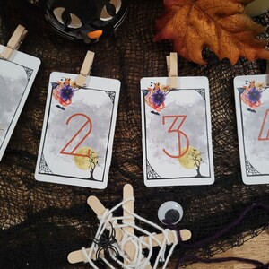 Può includere: Quattro carte a tema Halloween con i numeri 1, 2, 3 e 4 stampati su di esse. Ogni carta ha uno sfondo ad acquerello con una luna, un albero e pipistrelli. Le carte sono decorate con fiori e una ragnatela.