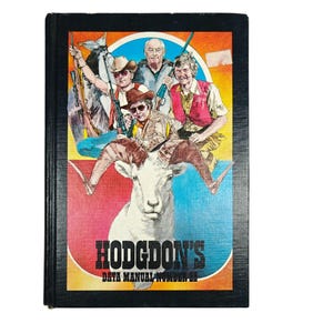 May include: A vintage hardcover book titled "Hodgdon's Data Manual Number 22." The cover features a colorful illustration of five men with rifles, riding a ram. The background has red, blue, and yellow hues.