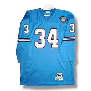 May include: Light blue vintage football jersey with the number 34 in white with maroon trim on the front. The number 3 is on each sleeve. The jersey has a V-neck and a patch on the upper right chest.