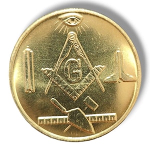 May include: A gold-colored metal coin with a Masonic symbol, including a compass, square, and a 'G' in the center. The coin also features an all-seeing eye and a level.
