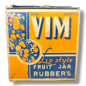 以下が含まれることがあります： ヴィムリップスタイルフルーツジャーラバーのヴィンテージボックス。ボックスはオレンジとブルーで、フルーツとジャーの絵が描かれています。ボックスのテキストは「Vim Lip Style Fruit Jar Rubbers」です。