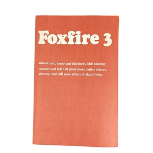 Puede incluir: Un libro rectangular titulado Foxfire 3 con una cubierta de color naranja terracota sólido. El texto blanco dice: Foxfire 3, animal care, banjos and dulcimers, hide tanning, summer and fall wild plant foods, butter churns, ginseng, and still more affairs of plain living.