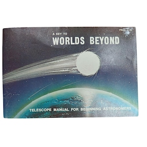 Puede incluir: Libro vintage titulado "A Key to Worlds Beyond" con una ilustración de temática espacial. La portada presenta un planeta blanco, un cometa y un planeta azul y verde. También es visible el texto "Telescope Manual for Beginning Astronomers".