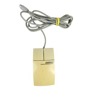 May include: A vintage Compaq computer mouse in a cream color, featuring two buttons and a wired connection. The mouse has the "COMPAQ" logo printed on the front. The gray cable is secured with a yellow rubber band.