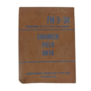 May include: A brown Department of the Army Field Manual titled FM 5-34 Engineer Field Data, dated December 1969. The cover features blue text and two horizontal blue lines, with handwritten text at the top reading I.T. VERBOSICK.