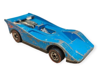 May include: A blue toy race car with black wheels and a silver interior. The car has a weathered, vintage look.