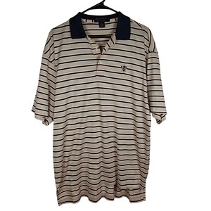 May include: A short-sleeved polo shirt with horizontal stripes in beige, black, and light orange. The shirt has a navy blue collar and a small emblem on the left chest. It is hanging on a black hanger.