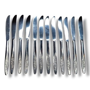 May include: A set of 12 silver dinner knives with floral designs on the handles.