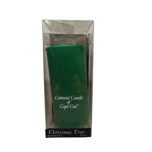 Puede incluir: Una vela de pilar verde en un paquete de plástico transparente. La vela está etiquetada como "Colonial Candle of Cape Cod" y "Christmas Tree Scented Pillar 8/750".