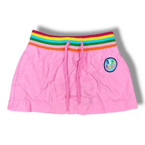 May include: Pink skirt with a rainbow elastic waistband and a colourful "OshKosh" logo patch.