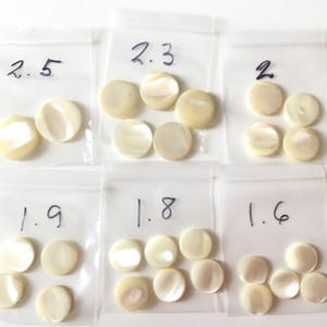 Peut inclure: Six petits sachets en plastique contenant plusieurs morceaux de coquillage nacré, ronds et plats, de couleur blanc cassé. Chaque sachet est numéroté de 1,6 à 2,5. Les coquillages ont un éclat nacré.