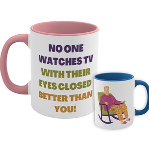 May include: White ceramic mug with a pink rim and handle. The mug has a funny saying that reads "No one watches TV with their eyes closed better than you!"  A cartoon illustration of a person sitting in a rocking chair is on the smaller mug.