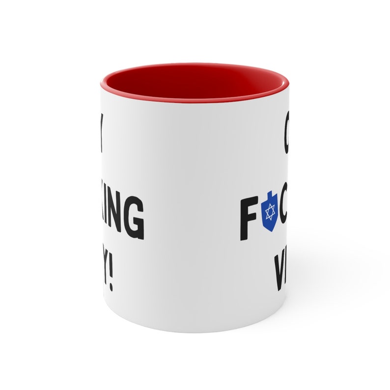 Puede incluir: Taza de caf&eacute; de cer&aacute;mica blanca con un borde rojo. La taza tiene texto negro que dice "Oy vey!" en el lado izquierdo y "F*ck yeah!" en el lado derecho. Una estrella de David azul est&aacute; al lado del texto en el lado derecho.