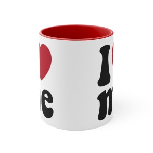May include: White ceramic mug with a red rim. The mug has a black heart with the word "me" and a black "I" with a red heart next to it.