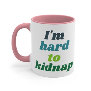 May include: White ceramic mug with a pink rim and handle. The mug has the text "I'm hard to kidnap" in colourful letters.