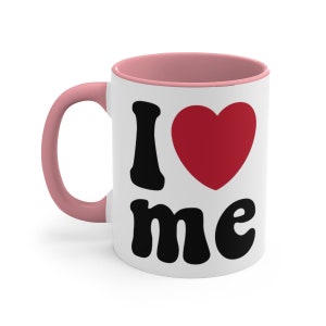 May include: White ceramic mug with a pink rim and handle. The mug has a black graphic that says "I love me" with a red heart.