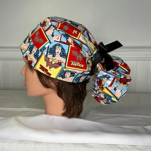 May include: A Wonder Woman themed scrub cap featuring a comic book print with the Wonder Woman logo and the words "Fight for Justice". The cap is predominantly red, blue, and yellow, with a black ribbon tie.