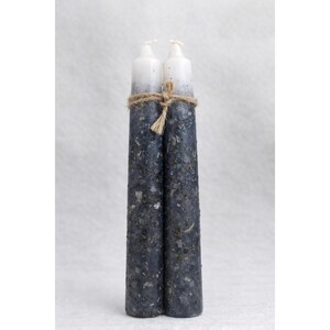 Puede incluir: Dos velas azul oscuro con la parte superior blanca, atadas con hilo. Las velas están decoradas con hierbas secas, lo que les da un aspecto rústico. Estas velas son un artículo decorativo.