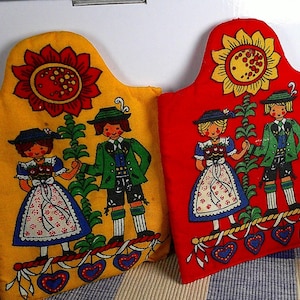 May include: A set of three ceramic mugs with a speckled, cream-colored glaze. Each mug features a different hand-painted design: a blue and green leaf, a yellow flower, and a red berry. The mugs have a simple, modern design.