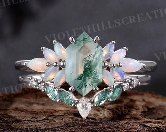 Può includere: Un set di anelli in argento con una pietra centrale in agata muschiata verde taglio smeraldo, circondata da accenti di opale. Il set include una fascia abbinata con ulteriori dettagli in opale e pietre preziose.