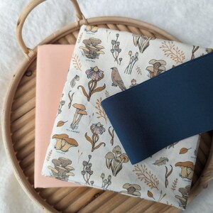 May include: A woven basket tray with a light pink fabric and a white fabric with a mushroom and floral print. The white fabric has the text "Yellowfoot" and "Oyster" printed on it.