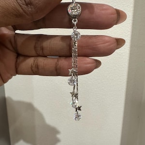 May include: A silver body jewelry piece with a large clear crystal and a dangling chain with smaller clear crystals and star charms.