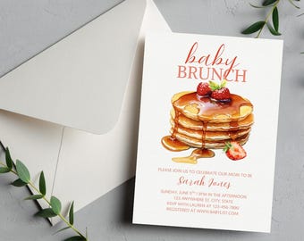 May include: Baby brunch invitation featuring a watercolor illustration of pancakes with syrup and strawberries. The invitation includes the text "baby brunch" in a script font, along with event details and the name "Sarah Janes". The invitation is accompanied by a white envelope.