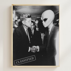 May include: Black and white framed print depicting a handshake between a man in a suit and an alien. The word "CLASSIFIED" is stamped on the bottom left corner. Other men in suits are in the background.