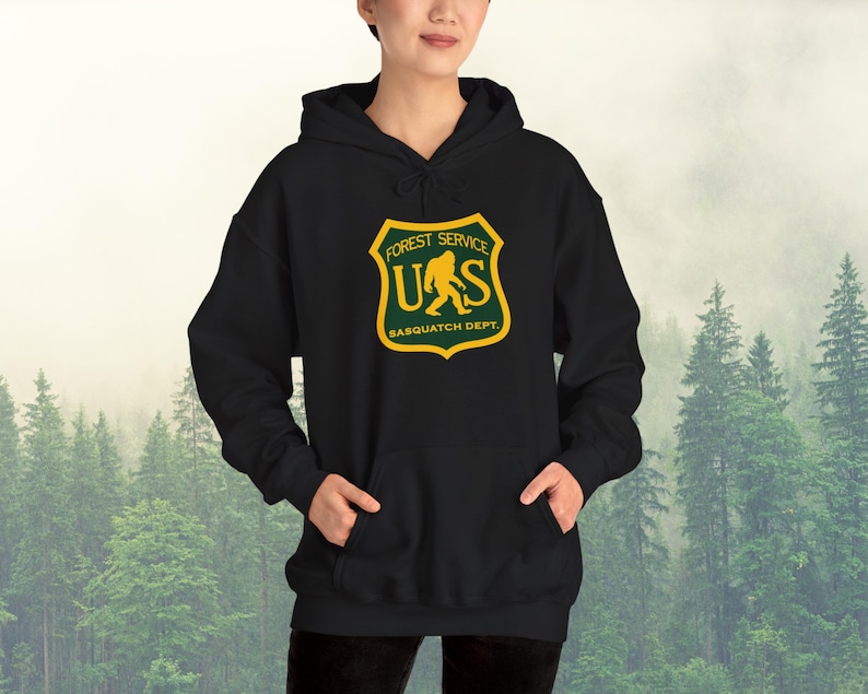 May include: Black hooded sweatshirt with a green and yellow graphic of a Bigfoot walking in front of the text "Forest Service US Sasquatch Dept."