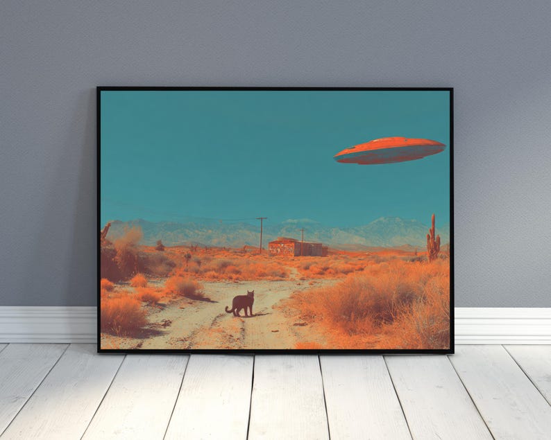May include: A framed art print depicts a desert landscape under a teal sky. An orange and red flying saucer hovers above. A black cat stands on a dirt road. The scene includes desert plants, a building, and mountains.