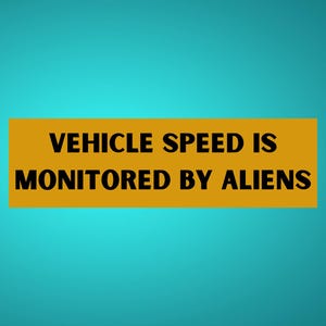 May include: A rectangular sign with the text "VEHICLE SPEED IS MONITORED BY ALIENS" in black letters on a gold background. The background is a teal color.