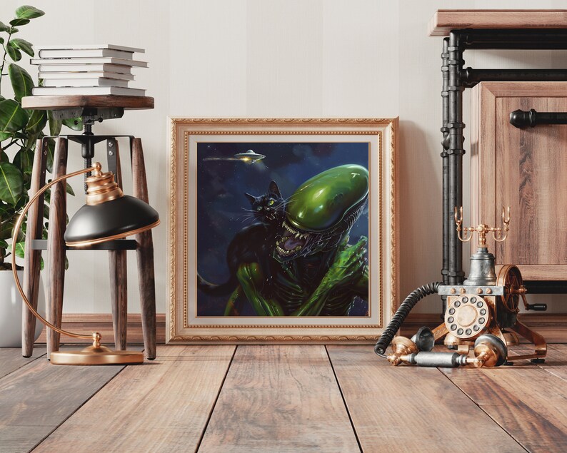 May include: A framed print of a green alien creature with a black cat. The alien has a large head and is holding the cat in its arms. The background is a dark blue with stars. The print is in a gold frame.