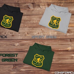 May include: Three hooded sweatshirts in black, forest green, and sport grey with a graphic print of a yellow Sasquatch inside a yellow shield with the text "Forest Service US Sasquatch Dept."