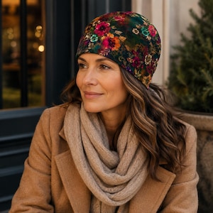 May include: A beanie hat featuring a dark green base with a vibrant floral pattern in shades of red, orange, pink, and teal. The hat is constructed from a soft fabric and fits snugly around the head, showcasing a detailed botanical print throughout.