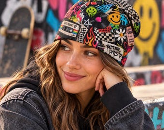 May include: A beanie featuring a vibrant, multi-colored collage print including a cassette tape with the text 'Good Music', a yellow smiley face, flames, checkerboard patterns, a white flower, and the handwritten-style text 'Better Days'.
