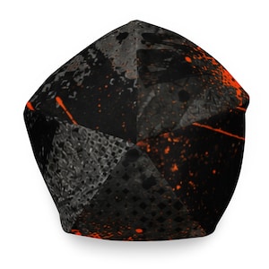 Top view of black and orange graphic beanie showing paneled construction, distressed urban artwork, charcoal textures and bright orange graffiti details.