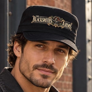 May include: A black military-style cadet cap featuring a graphic print on the front. The design includes the text "THE BLACKSMITHS ARMS" in a gold serif font, accompanied by an illustration of an anvil, a hammer, and a horseshoe.