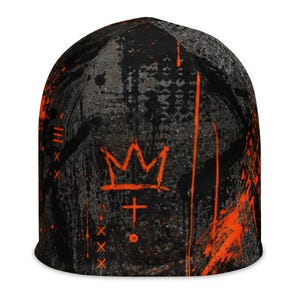 Black and orange grunge beanie with distressed graffiti print, abstract textures, paint splatter and bold orange crown graphic, unisex alternative streetwear hat.