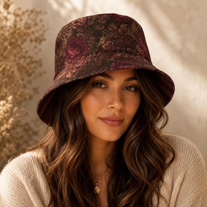 Peut inclure: Un chapeau bob orné d'un motif floral sombre et mélancolique, composé de roses bordeaux et brunes sur un fond noir. Le chapeau présente une calotte arrondie et un bord incliné vers le bas, fabriqué dans un tissu à la texture dense et visible.