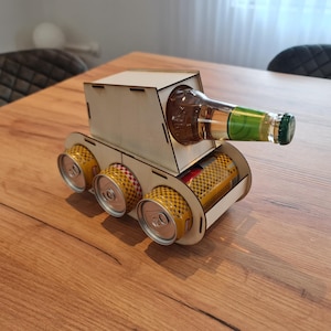 以下が含まれることがあります： ビール瓶を砲身、ビール缶を車輪に見立てた木製の戦車型ビールホルダー。 ビール瓶には緑と金のラベルが付いています。 ビール缶は黄色と銀色です。