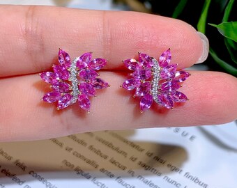 May include: A pair of pink sapphire earrings with a floral design. The earrings are set in gold and feature a row of diamonds.
