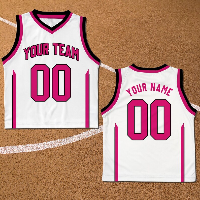 May include: White basketball jersey with black and pink trim. The front of the jersey says "YOUR TEAM" and has the number "00" in pink. The back of the jersey says "YOUR NAME" and has the number "00" in pink.