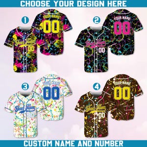 May include: Four baseball jerseys with custom name and number options. Each jersey features a unique design with colorful splatter patterns. The text "CHOOSE YOUR DESIGN HERE" and "CUSTOM NAME AND NUMBER" are displayed.