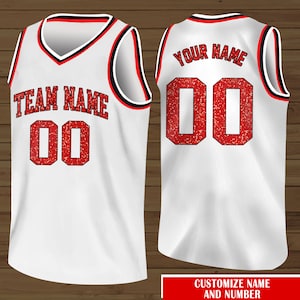 Puede incluir: Camiseta de baloncesto blanca con letras de purpurina roja. La parte delantera de la camiseta dice "TEAM NAME 00" y la parte trasera dice "YOUR NAME 00".