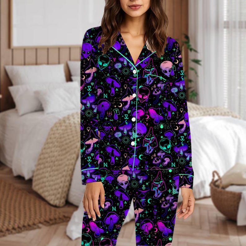 Peut inclure: Ensemble de pyjama noir avec un motif vibrant de champignons violets, de t&ecirc;tes d'extraterrestres et de symboles c&eacute;lestes. Le haut &agrave; manches longues et le pantalon ont une bordure turquoise et des boutons blancs. Le pyjama est en mati&egrave;re douce et confortable.