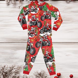 May include: A long-sleeve pajama set in bright red featuring an all-over print of Santa Claus riding motorcycles. The design includes green Christmas trees, gold bells, and red poinsettia flowers. The shirt and pants have solid red ribbed cuffs.