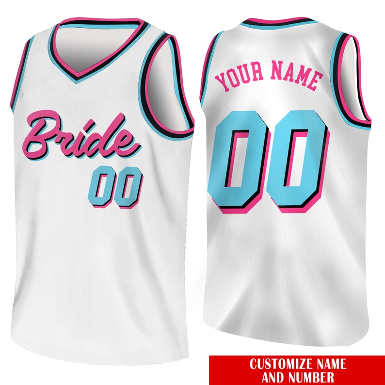 May include: White basketball jersey with pink and blue accents. The front of the jersey says "Bride" and has the number "00" on it. The back of the jersey has the text "YOUR NAME" and the number "00".