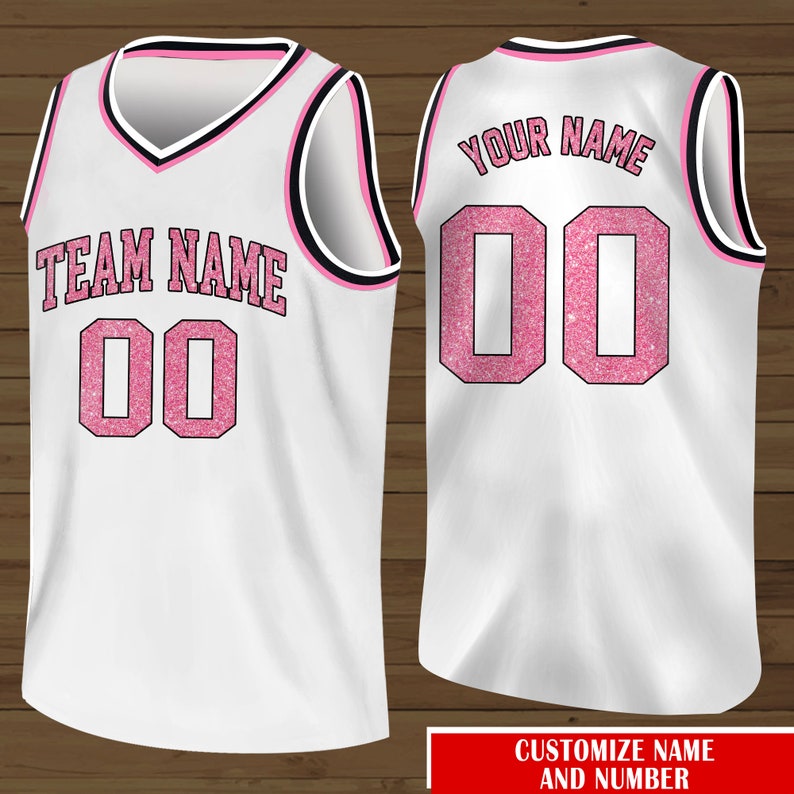 Puede incluir: Camiseta de baloncesto blanca con letras de purpurina rosa. La parte delantera de la camiseta dice "TEAM NAME 00" y la parte trasera dice "YOUR NAME 00".