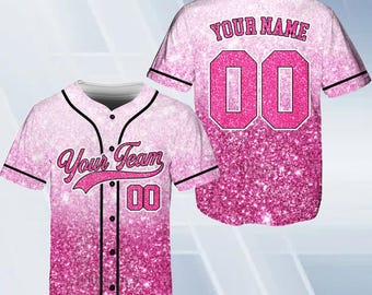 Pode incluir: Camisola de beisebol rosa e branca com design de glitter. A camisola tem um colarinho e mangas pretas. O texto "Your Team" está na frente da camisola, e o número "00" está na frente e atrás. O texto "Your Name" está nas costas da camisola.