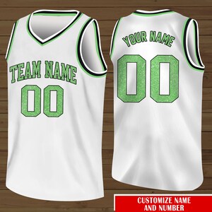 Puede incluir: Camiseta de baloncesto blanca con detalles de purpurina verde. La parte delantera de la camiseta dice "TEAM NAME 00" y la parte trasera dice "YOUR NAME 00".
